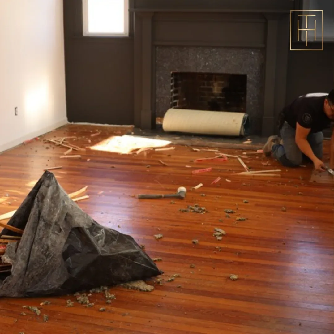 Hardwood floor installation in progress with technician fitting planks in Villanova PA living room with fireplace