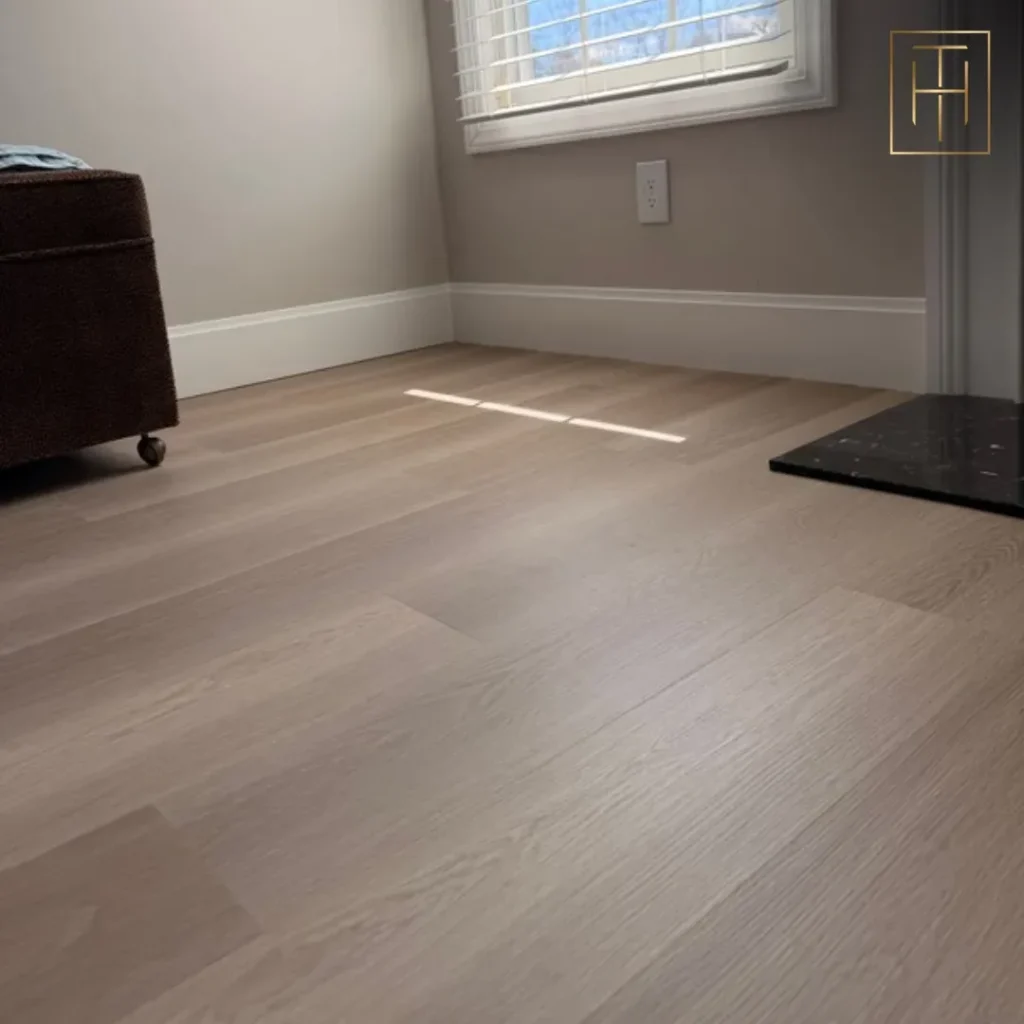 Light vinyl plank flooring in Haddonfield NJ bedroom with neutral walls and ottoman