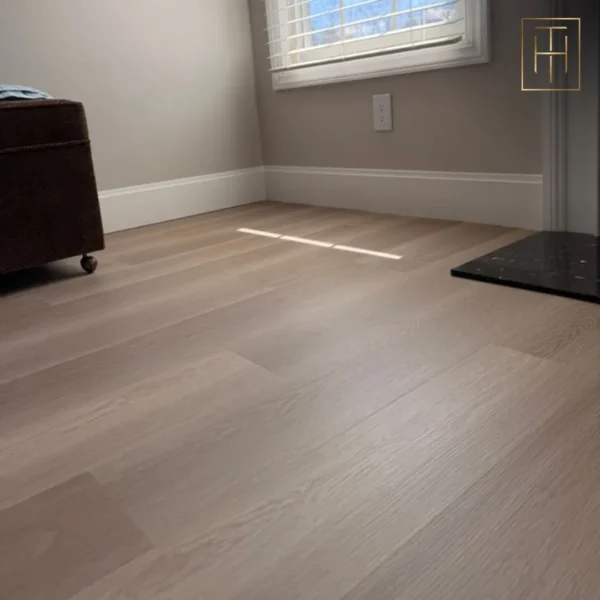 Light vinyl plank flooring in Haddonfield NJ bedroom with neutral walls and ottoman