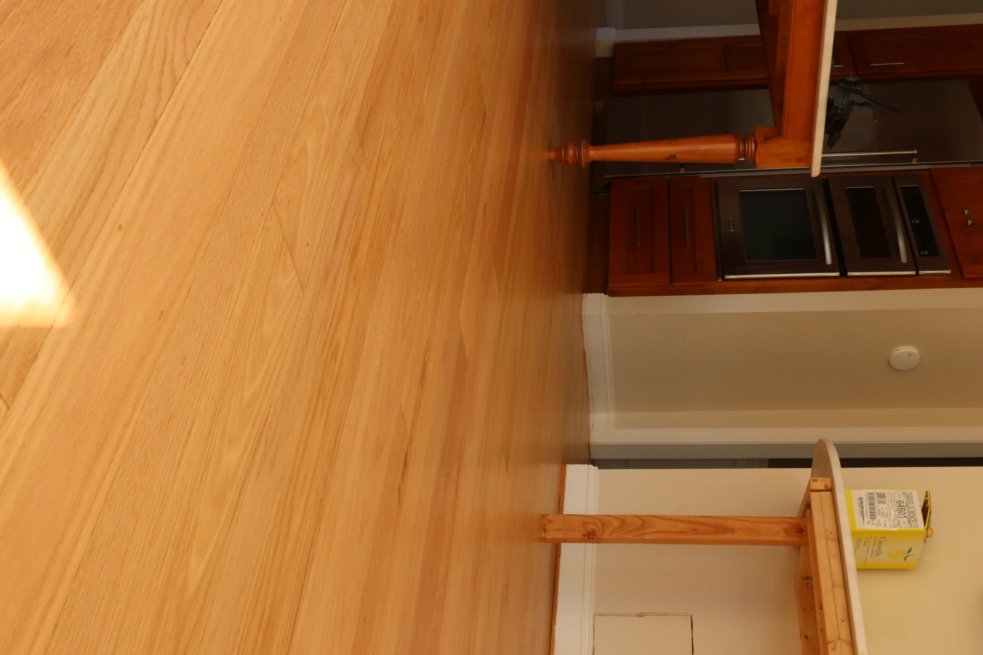 Light natural hardwood floors in a kitchen with dark wood cabinets and stainless steel appliances. by Tesla Hardfloor in Blue Bell, PA