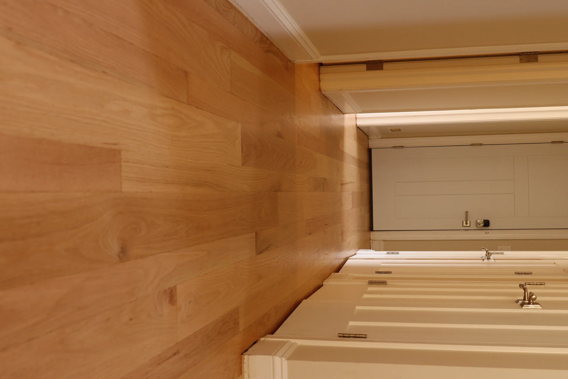 Newly installed light natural hardwood flooring next to white cabinets with metal hardware. by Tesla Hardfloor in Glenside, P
