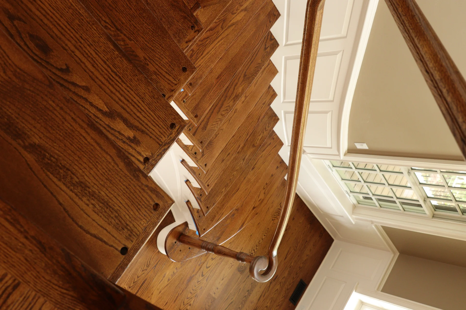Beautiful dark stained hardwood stairs with white risers and a matching handrail. by Tesla Hardfloor in Radnor, PA