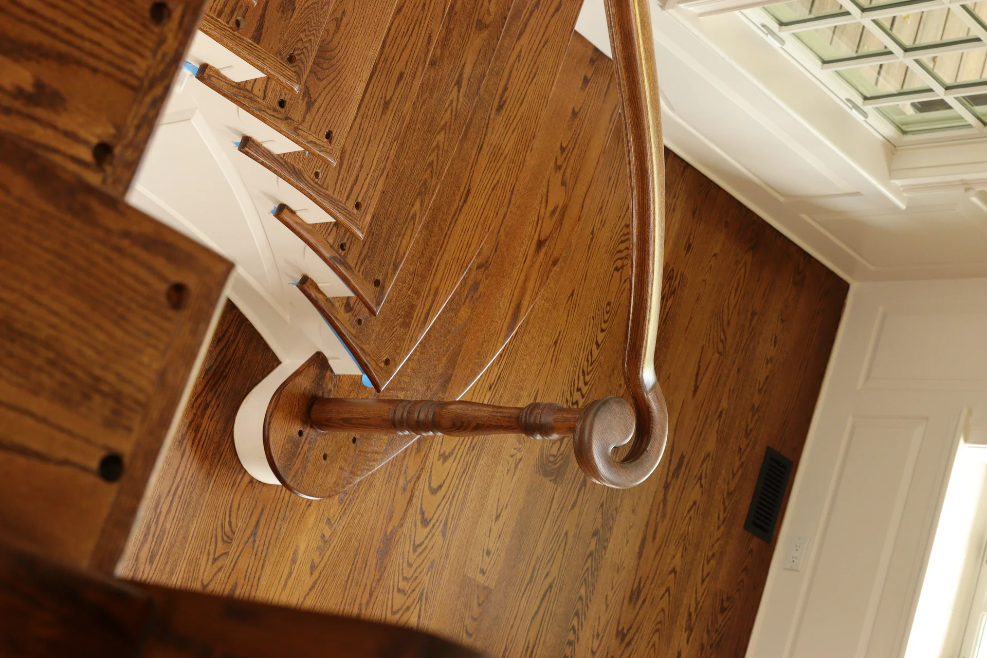 Overhead view of finished hardwood stairs and landing with white risers and railing. by Tesla Hardfloor in Blue Bell, PA