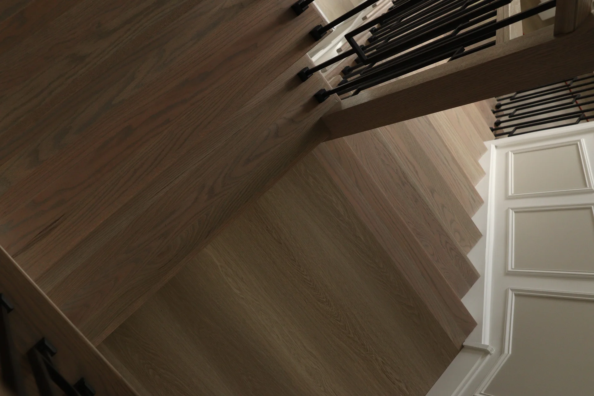 Overhead view of newly installed light brown wood stairs with black metal railings. by Tesla Hardfloor in Radnor, PA