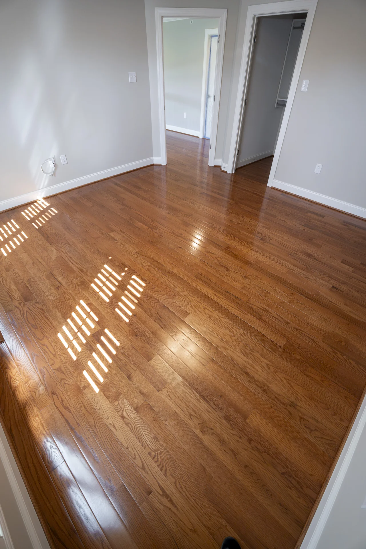 Glossy Refinished Hardwood Floors in West Chester, PA Beautifully refinished hardwood floors with a warm, glossy finish in a bright, empty room. by Tesla Hardfloor in West Chester