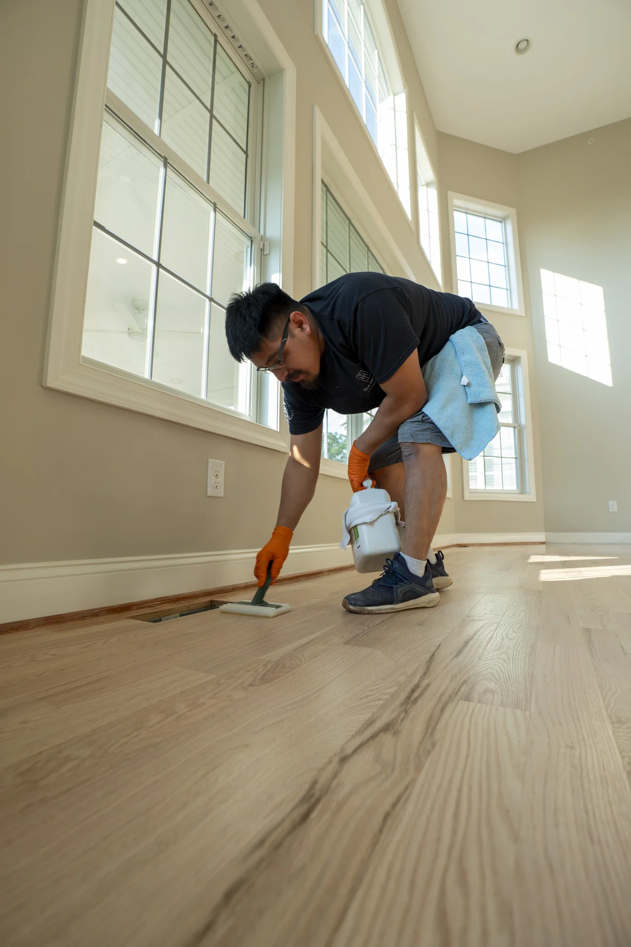 Applying Finish to Hardwood Floors in Villanova Worker applying finish to newly installed light hardwood flooring in a bright room. by Tesla Hardfloor in Villanova, PA