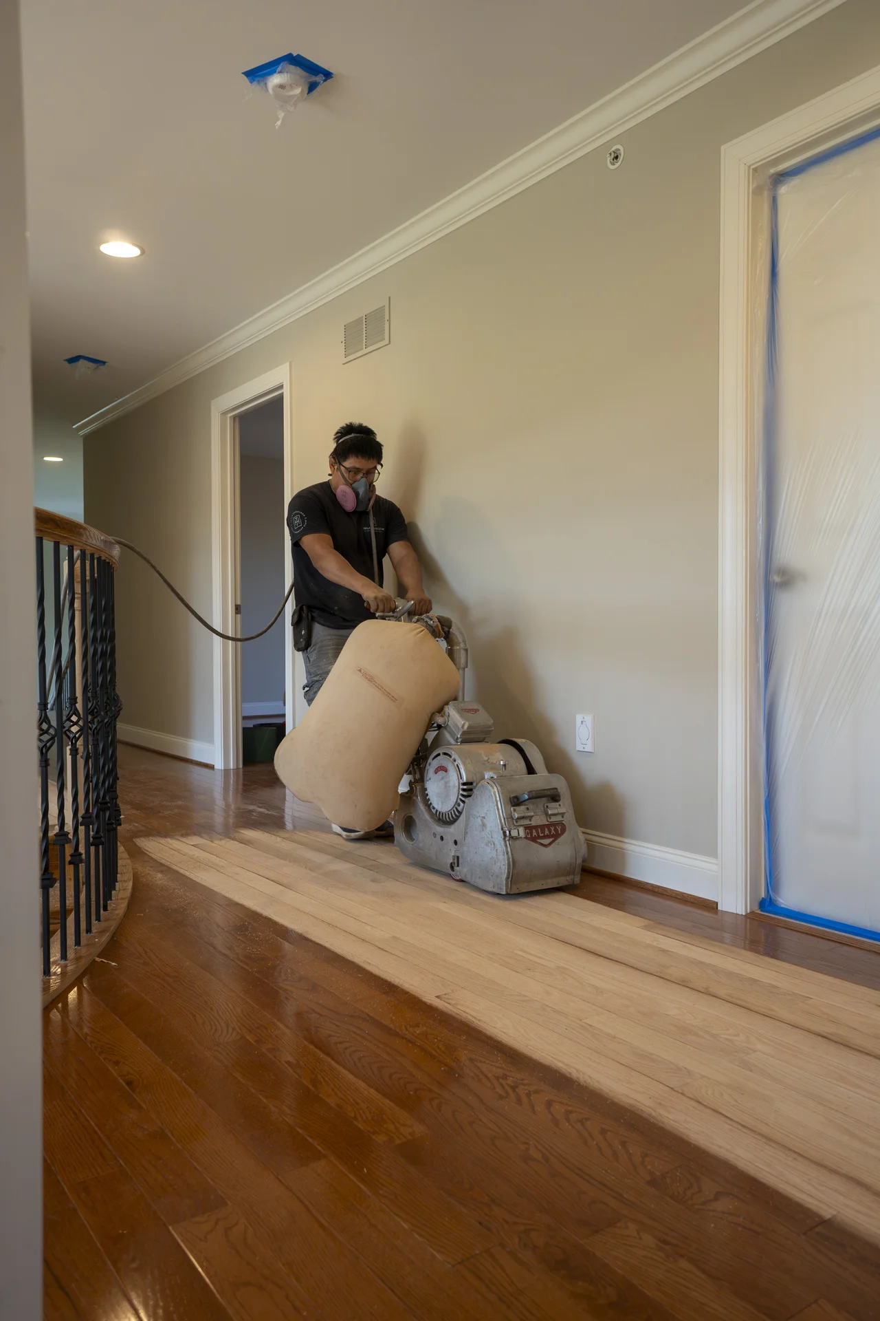 Practical Flooring for Busy Homes Worker sanding old hardwood floors to reveal natural wood grain in a home hallway. by Tesla Hardfloor in Doylestown, PA
