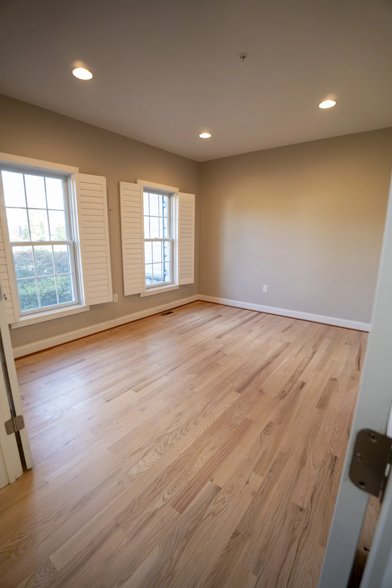 Empty room with newly installed light natural hardwood flooring, beige walls, and white trim. by Tesla Hardfloor in Moorestow