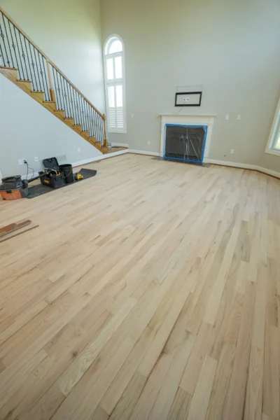 Light-colored plank hardwood flooring installation with tools and materials in a room by Tesla Hardfloor in Doylestown, PA