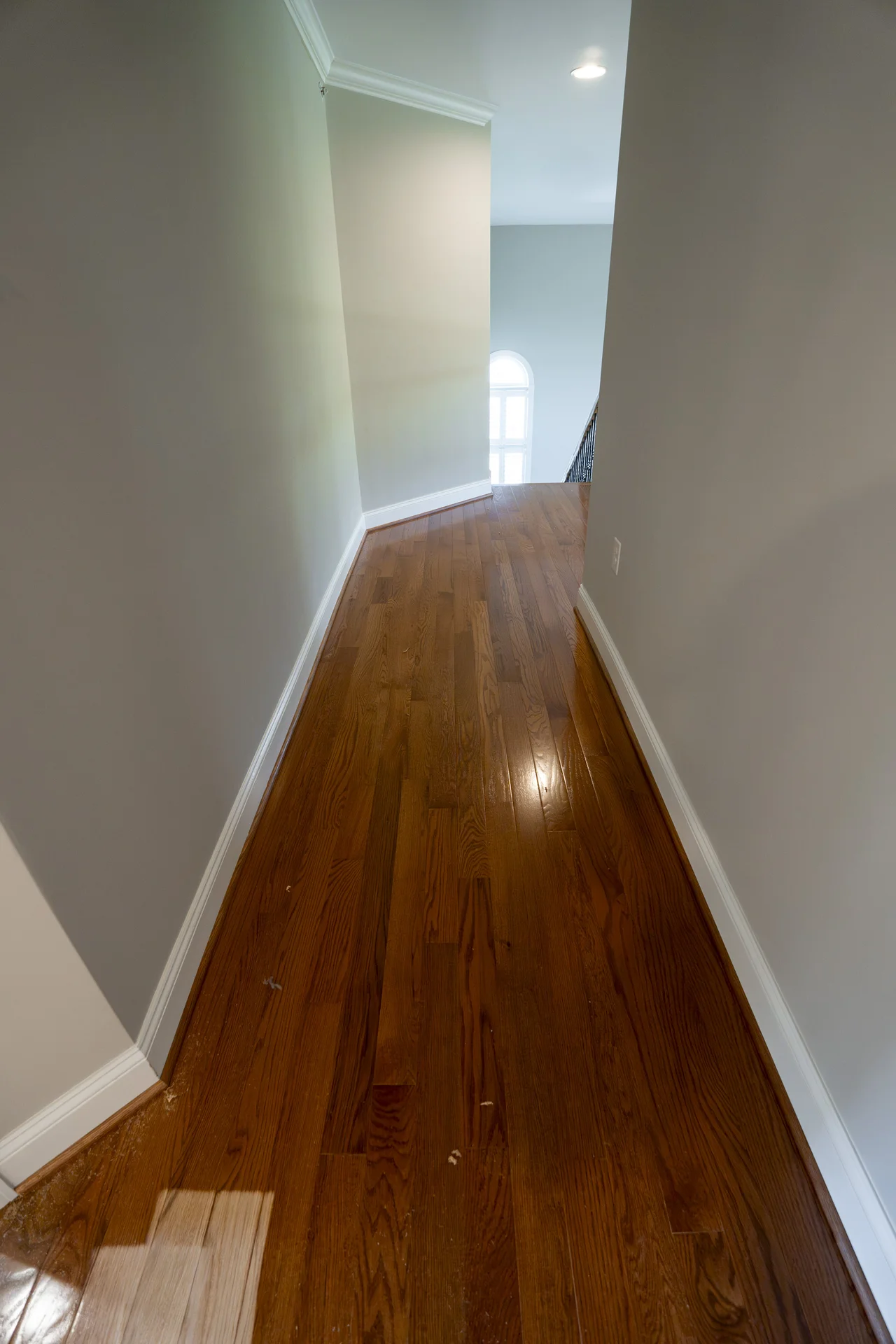 Reddish-brown Hardwood Flooring in a Hallway Long, narrow hallway with rich reddish-brown hardwood flooring and light gray walls. by Tesla Hardfloor in Villanova, PA