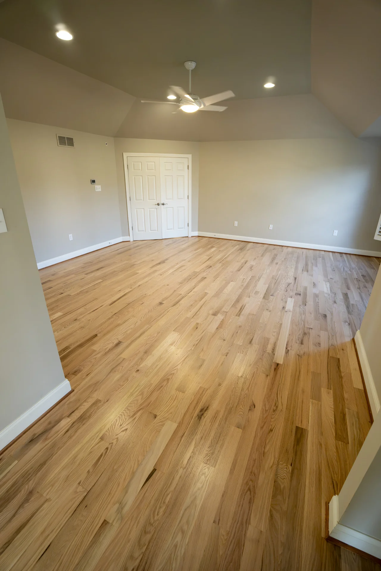 Newly installed light-colored hardwood flooring in a spacious, empty room with white trim. by Tesla Hardfloor in Blue Bell, PA