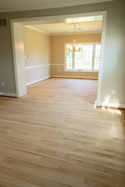 Newly installed light natural hardwood flooring in an empty dining room with a chandelier. by Tesla Hardfloor in Radnor, PA