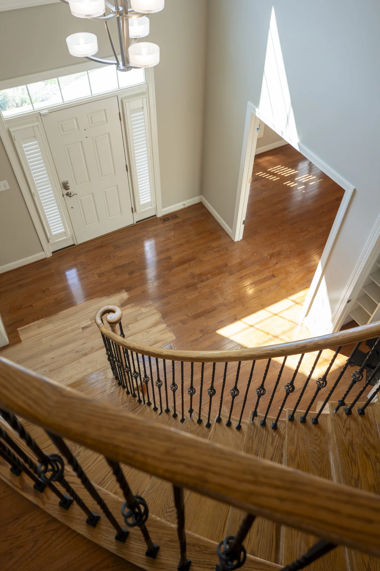 Grand Curved Staircase Installation in Blue Bell, PA High-angle view of a grand entryway with curved wooden stairs and dark hardwood floors. by Tesla Hardfloor in Blue Bell, PA