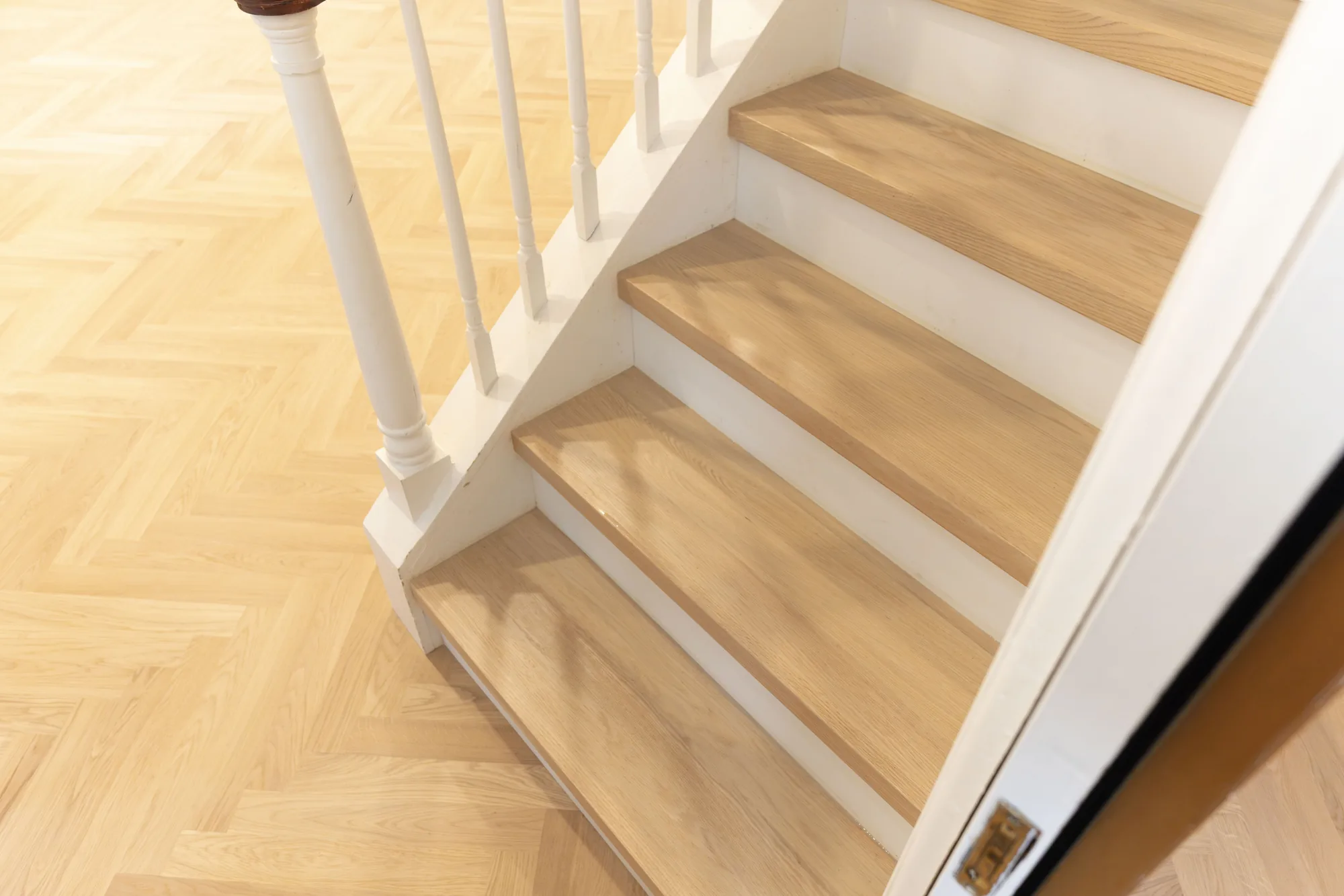Hardwood stair treads with white risers finished to match a herringbone floor in Lafayette Hill, PA by Tesla Hardfloor