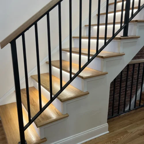 Stair installation and restoration with wood steps and black railing by Tesla Hardfloor